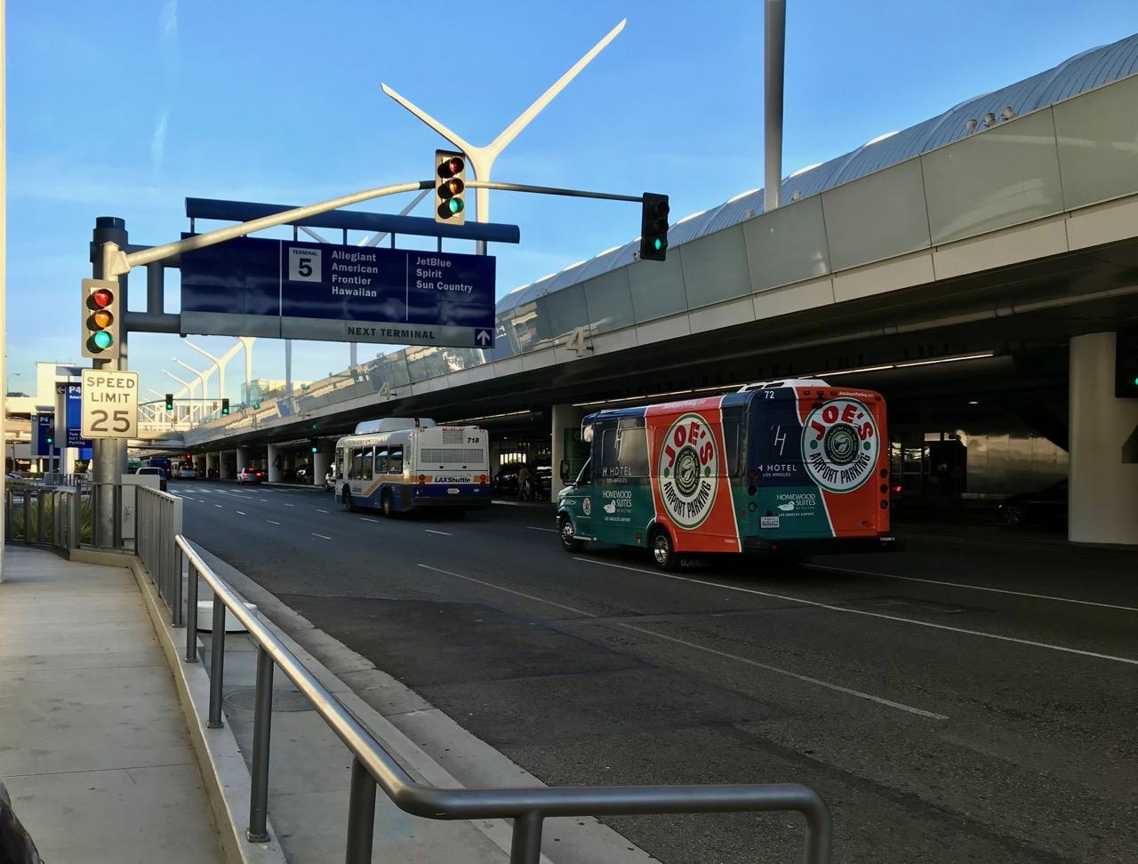 Hotel and private parking shuttles at an LAX terminal pickup area