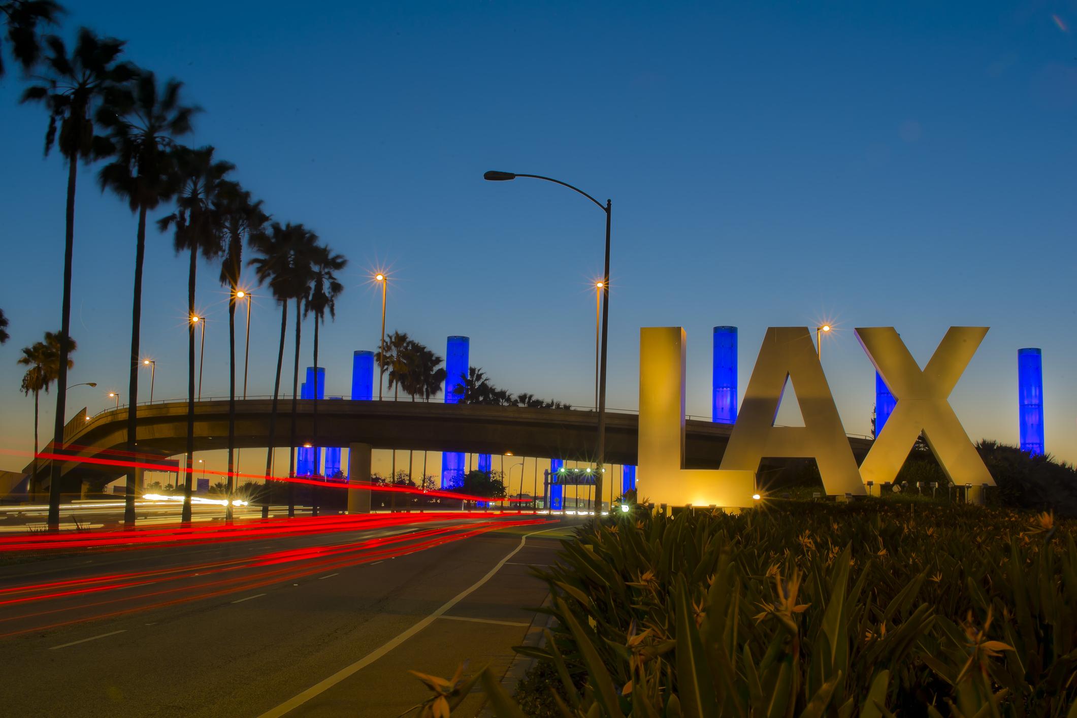 LAX airport entrance at dawn with illuminated sign and traffic lights