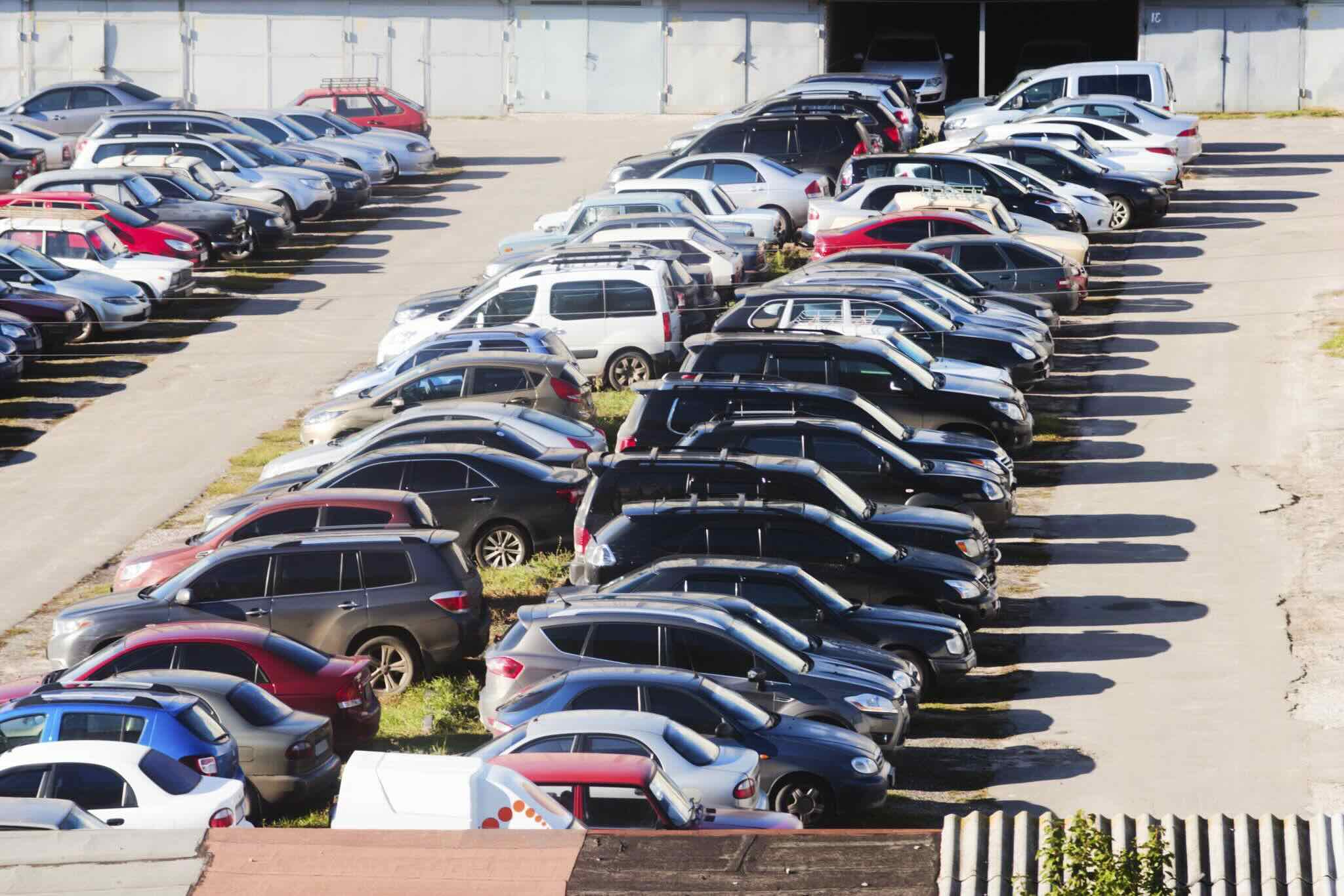 Open parking lot with cars exposed to direct sunlight near airport