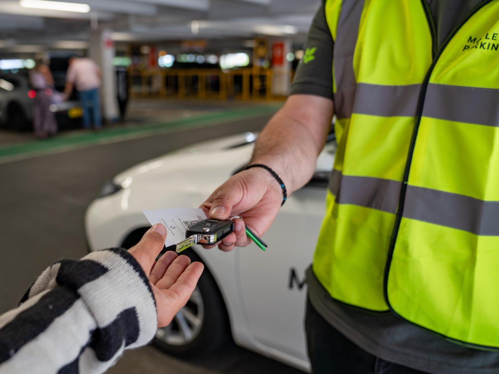 Traveler receiving car keys from valet staff at an airport parking lot