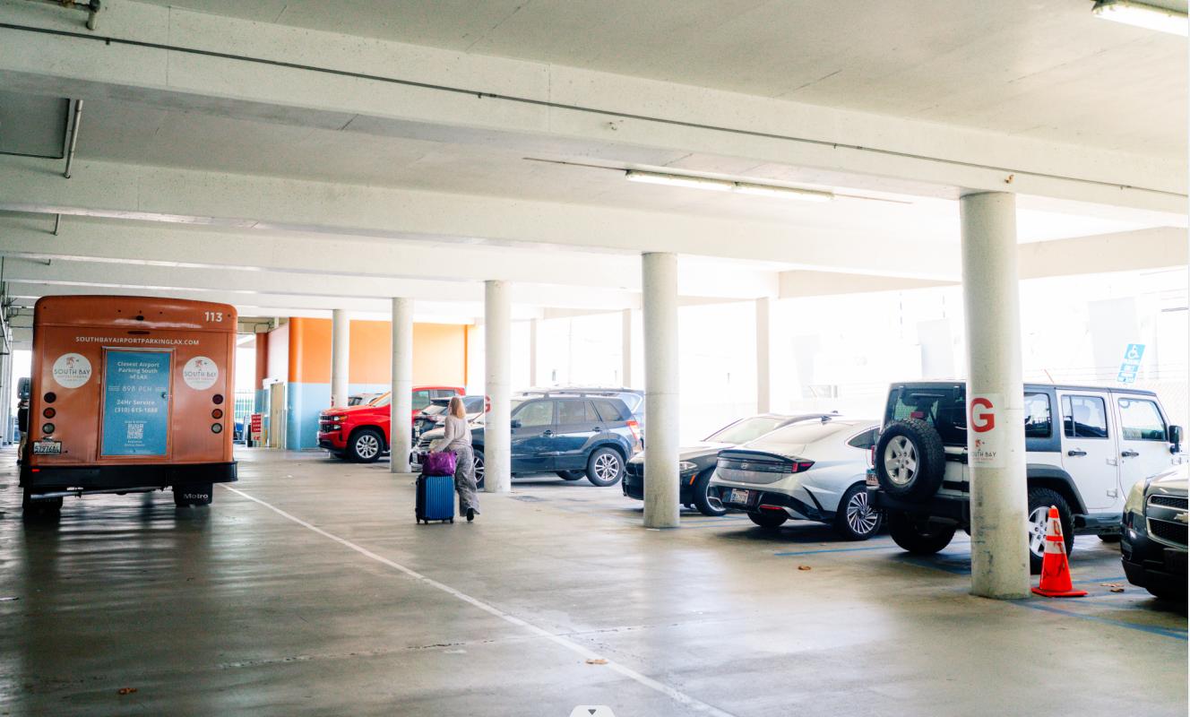 Traveler with luggage walking through a covered LAX parking garage