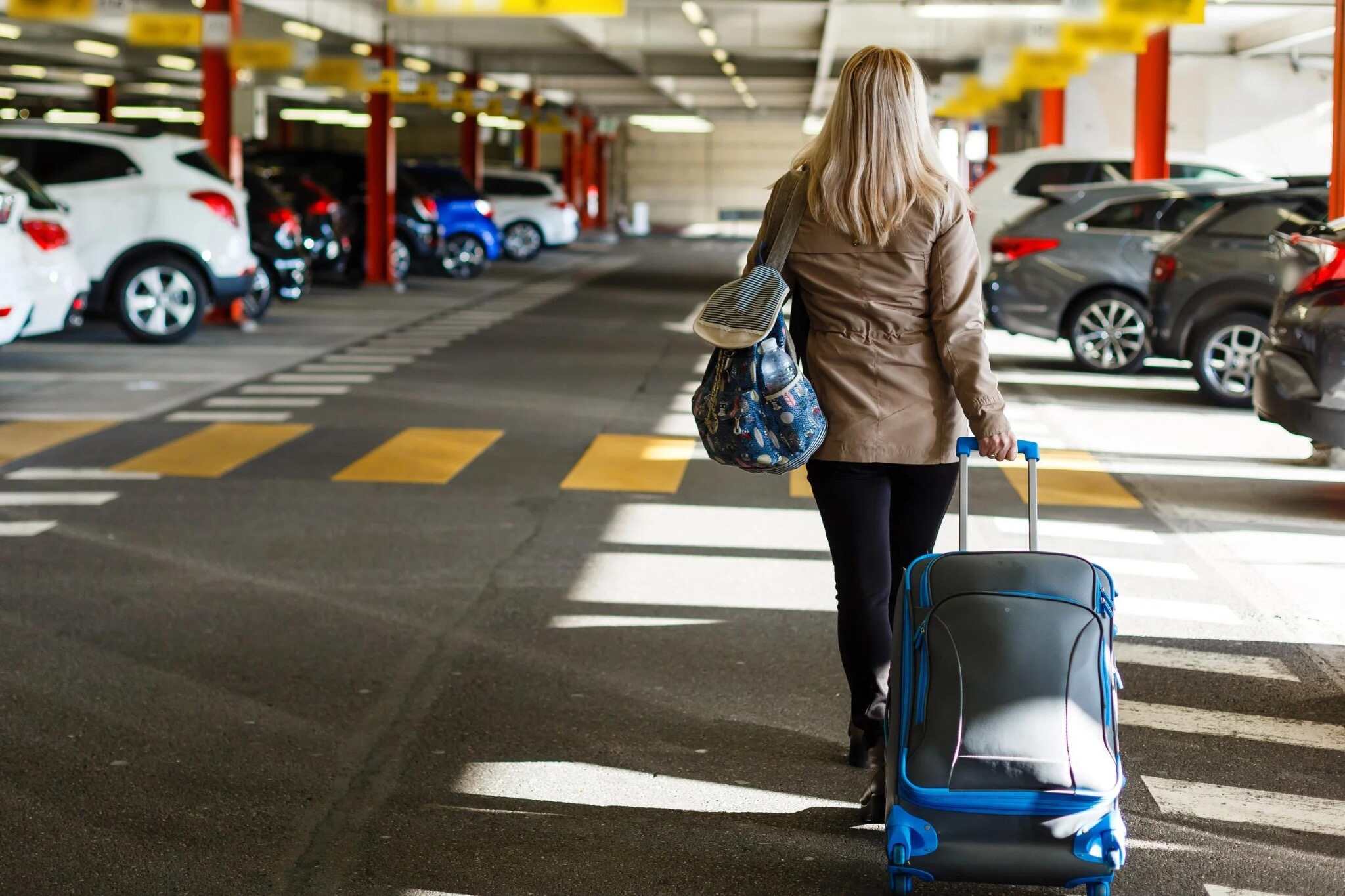 Traveler with luggage walking through an airport parking garage