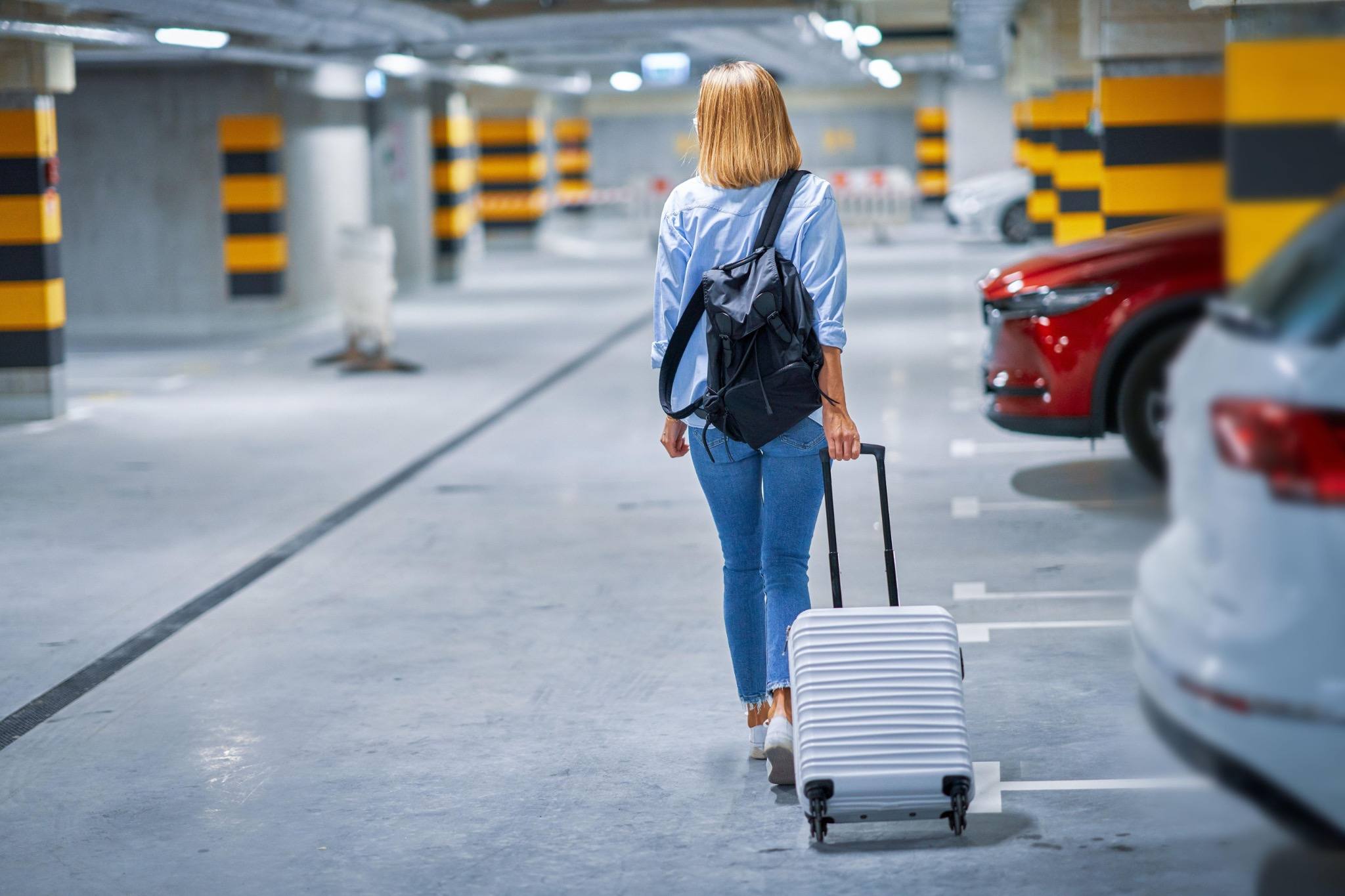 Traveler with suitcase walking through an airport parking garage at night