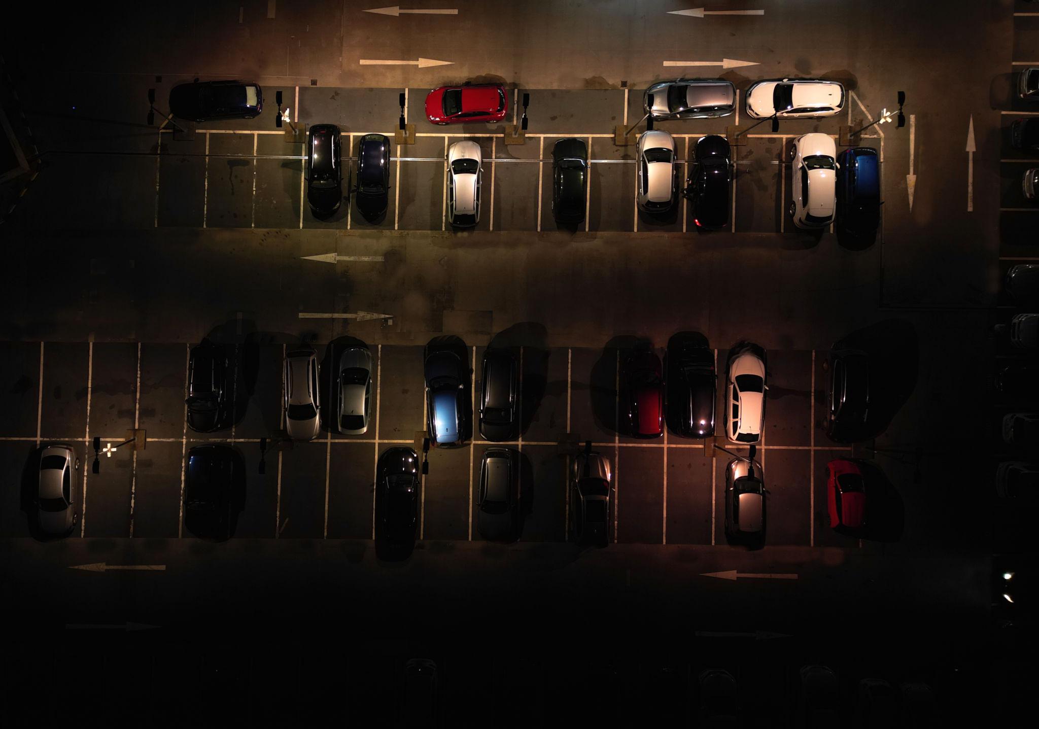 poorly lit parking lot at night with limited visibility and parked cars